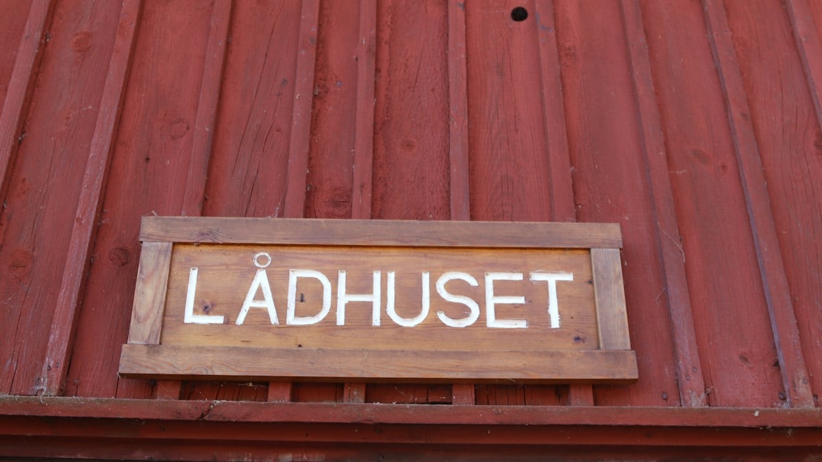 A wooden sign with "lådhuset" is shown